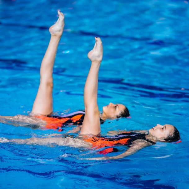 Duo of waterdancer girls in the pool doing routine, competitive stream program