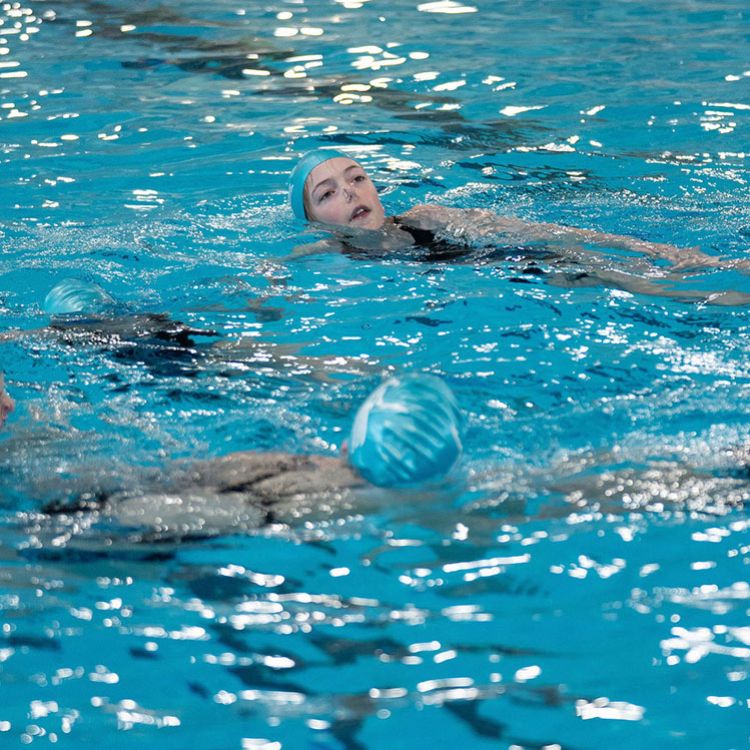 Artistic swimmer girls in pool with hands in the air
